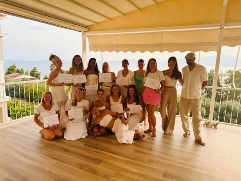 Yoga-Teilnehmerinnen mit Zertifikaten auf einer Terrasse am Meer