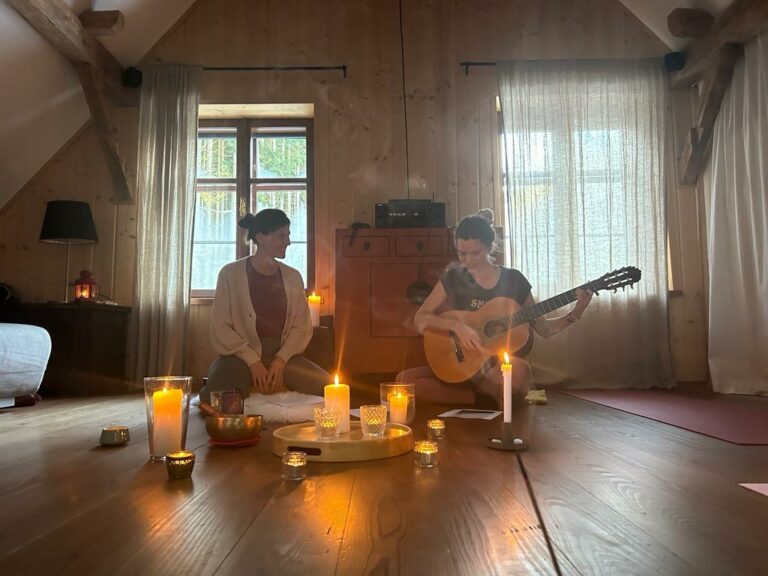 Yogalehrerin spielt Gitarre zwischen Kerzen bei einer Klang- und Meditationsrunde